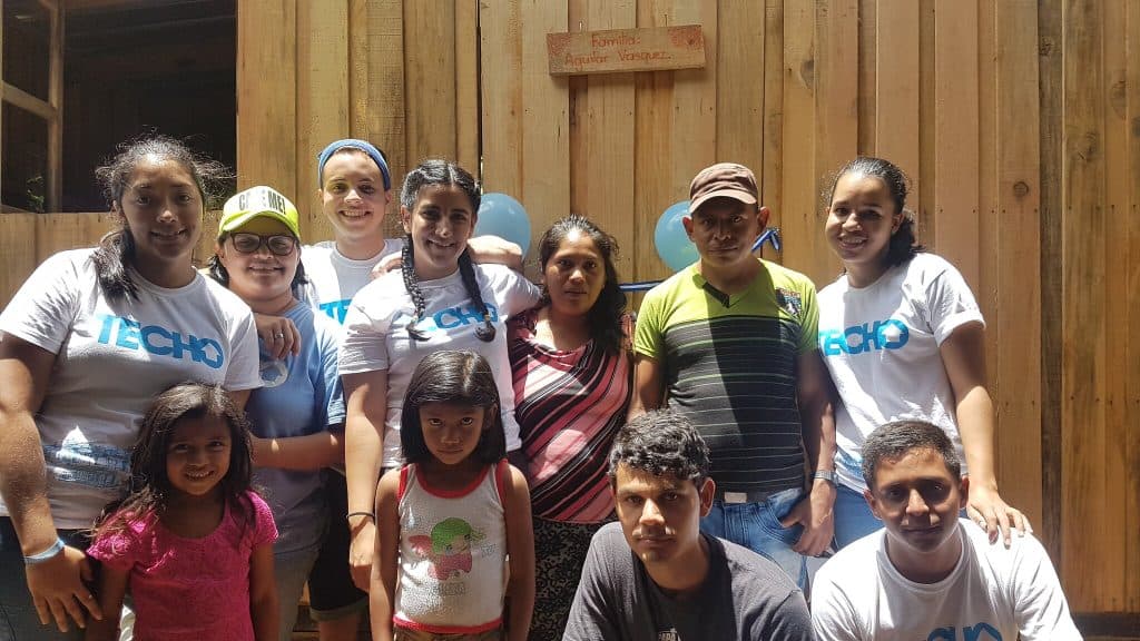 grupo de voluntarios junto con familia de comunidad luego de terminar la vivienda
