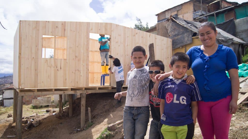 Madre de familia abrazada feliz con sus hijos mientras se construye su vivienda